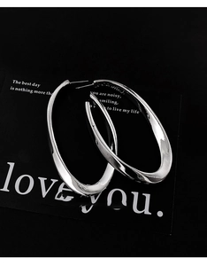 Detailed view of polished silver oval hoop earrings with high gloss metallic finish