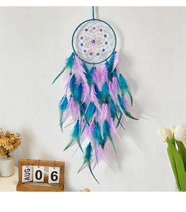 Detail of handcrafted blue beads mesh and vibrant feathers on a dreamcatcher pendant