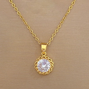 Detail of gold necklace featuring a sparkling circular cubic zirconia pendant charm
