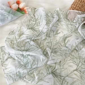 Macro detail of breathable sheer silk scarf featuring green bamboo and leaf patterns