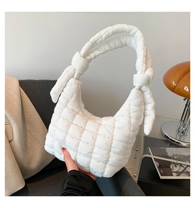 Detail of white quilted cloud bag featuring soft padded texture and unique knotted shoulder strap