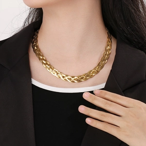 Close-up of golden woven snake chain necklace worn by a model with a metallic texture
