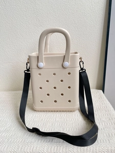 Detail of cream white EVA tote bag featuring circular vent holes and detachable black strap