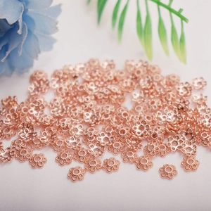 Macro shot of rose gold flower bead caps for DIY jewelry making with petals