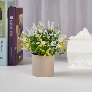 Macro detail of artificial potted plant with green leaves and white spikes in beige pot