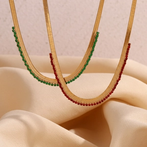 Detailed close-up of gold snake chain necklaces with green and red zircon inlays