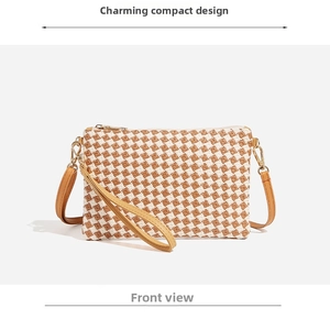 Detail of woven straw handbag featuring brown and white checkered pattern and gold hardware