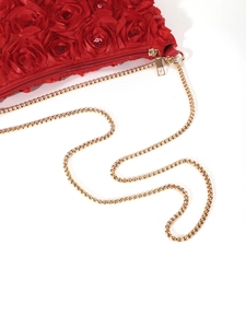 Close-up of red 3D rose petals with sequins and gold chain strap on a satin evening bag