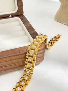 Detail of 18K gold-plated watchband style bracelet with white zircon on wooden box