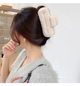 Detailed view of a large beige plush square shark hair claw clip on a female model