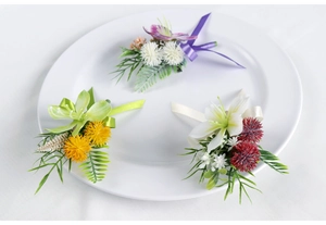 Detailed view of handmade silk wedding corsages in purple, yellow, and red color sets