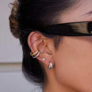 Close-up of model wearing geometric titanium steel C-shaped earrings and gold ear cuffs