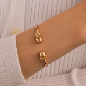 Bracelet manchette tête de mort gothique dorée porté au poignet pour femmes