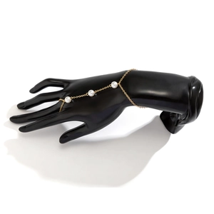 Detail of gold chain hand chain with white pearls on a black mannequin display