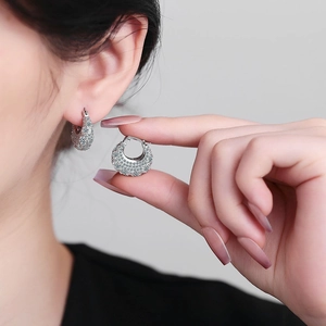 Close-up of sparkling zircon purse-shaped silver earrings worn by a model