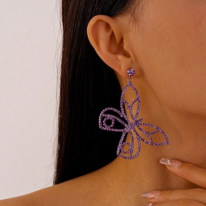 Close-up of sparkling purple butterfly earrings with rhinestones on a female model