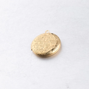 Macro detail of a 316L gold stainless steel locket with vintage floral engravings