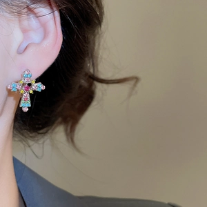 Close-up of cross pendant earring featuring vibrant multi-color rhinestones in silver finish