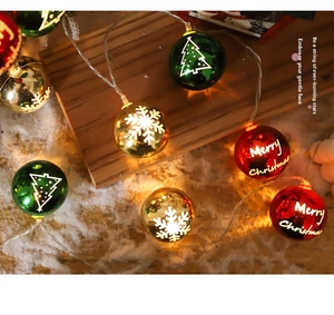 Detail of Christmas LED string lights with red green gold balls on snowy background