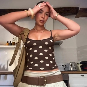Dettaglio di un top a pois marroni in maglia a coste con spalline sottili e vestibilità slim