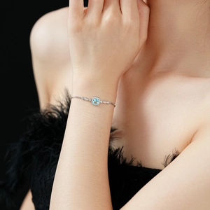 Detail of adjustable silver bracelet with square light blue zircon on model's wrist