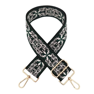 Detail of adjustable green jacquard embroidered bag strap with golden metal hardware