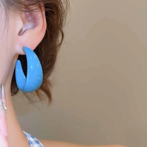 Detailed view of model wearing minimalist blue resin C-shaped hoop earrings