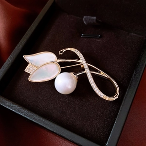 Détail d'une broche fleur plaquée or 14K avec nacre et perles sur satin sombre