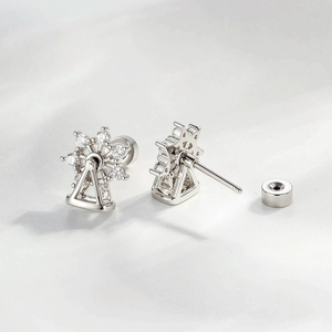 Rotating Ferris wheel cartilage earrings with crystals on soft white fabric background