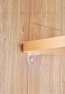 Macro detail of clear adhesive shelf support brackets installed on a wooden cabinet panel