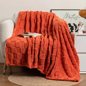 Detail of orange checkered plush blanket draped over white sofa in cozy room setting