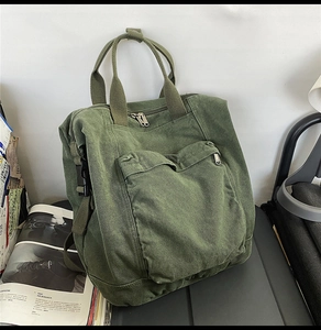 Detail of army green canvas backpack with large front zip pocket and reinforced handles
