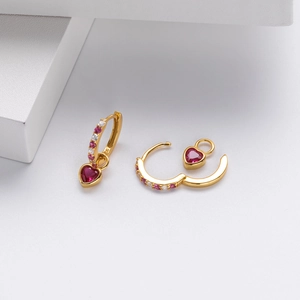 Macro shot of S925 sterling silver heart earrings with red gemstones and gold plating
