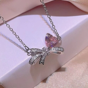 Pink heart and bow zircon necklace set in silver finish on soft silk background