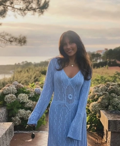 Détail d'une robe au crochet bleu clair montrant des motifs ajourés et un col en V