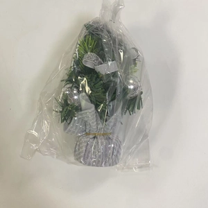Miniature artificial Christmas tree with silver ribbons and ornaments in clear bag
