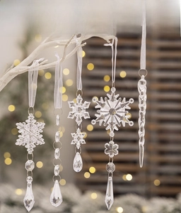 Detail showing five clear acrylic Christmas snowflake and icicle ornaments hanging on a branch