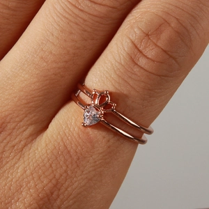 Detail view of rose gold crown ring with a heart-shaped crystal on model's finger