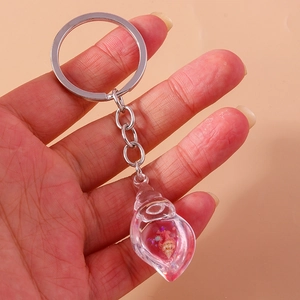 Macro detail of conch pendant keychain with internal sea shells and pink flowing glitter