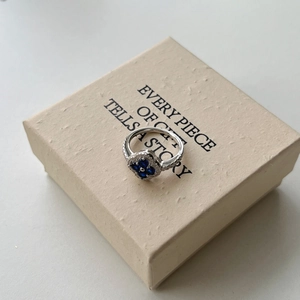 Macro shot of silver ring featuring blue heart-shaped cubic zirconia and clover motif