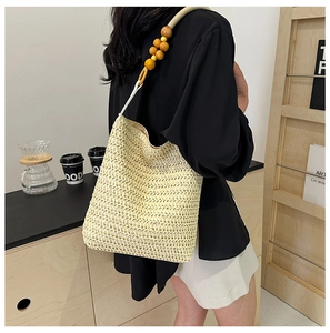 Detail of hand-woven straw shoulder bag with unique wooden bead strap for casual summer style
