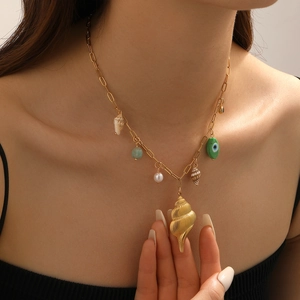 Close-up of gold ocean necklace featuring seashell, pearl and green bead pendants