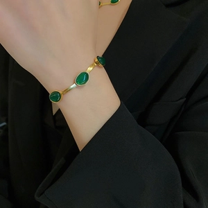 Vintage titanium steel gold bracelet with five emerald green stones on model wrist