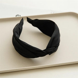 Close-up of black knotted headband with premium matte texture in a minimalist tray
