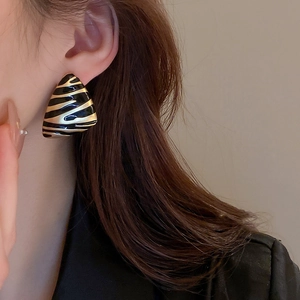 Close-up of triangle black and gold zebra pattern earrings worn by a model
