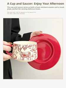 Detail of hand holding a ceramic coffee cup with red deer motif and matching saucer