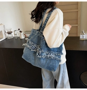 Gros plan détaillé du sac cabas en denim bleu avec franges et broderies sur la bandoulière