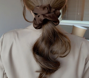 Detailed view of an oversized dark brown satin silk scrunchie on a ponytail