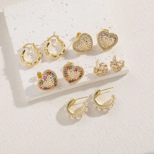 Vue détaillée d'un ensemble de boucles d'oreilles dorées avec perles et cœur en zircon