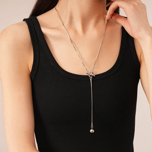 Detail of silver Y-shaped sweater necklace featuring a toggle clasp and metallic ball pendant
